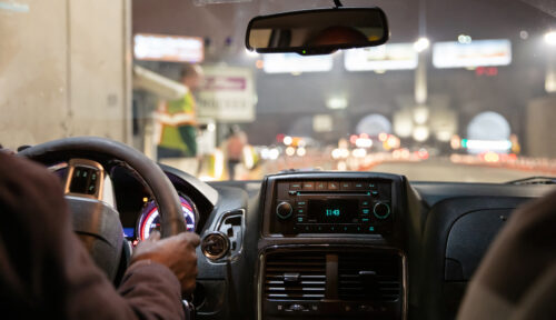 Driving in New York at night. Interior view of taxi cab. Close up view on the dashboard and drivers hand.