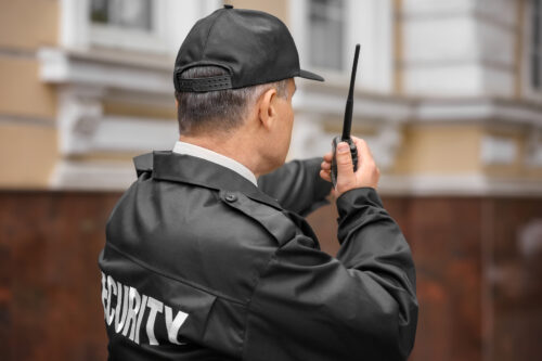 Male security guard using portable radio outdoors