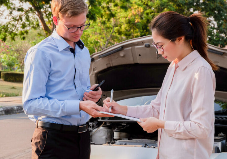 Insurance agent writing document on clipboard examining car after accident, Insurance concept