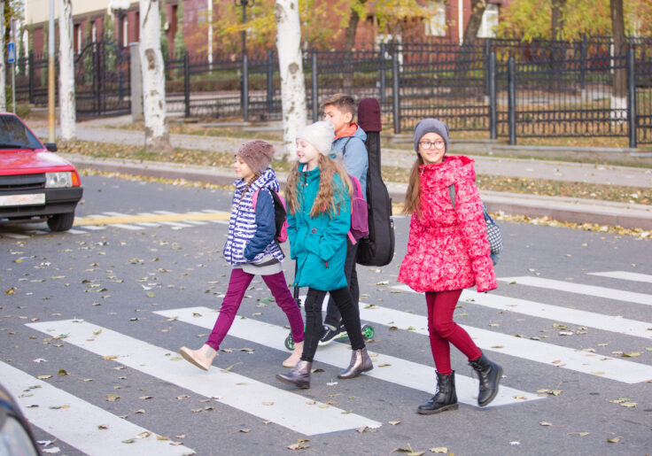 children go to school on the sidewalk with a fun company