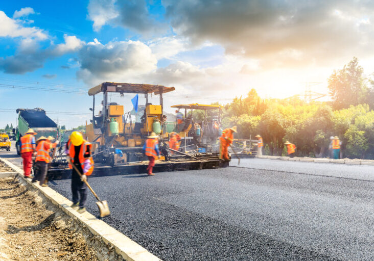 Construction site is laying new asphalt road pavement,road construction workers and road construction machinery scene.