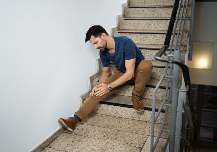 Man Sitting On Staircase After Slip And Fall Accident